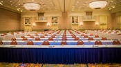 Varias filas consecutivas de mesas y sillas en un salón de eventos