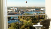 A hotel room balcony with a view of a passenger balloon hovering over Disney Springs across a lake