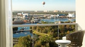 A hotel room balcony with a view of a passenger balloon hovering over Disney Springs across a lake