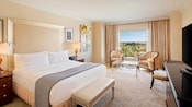 Une chambre d'hôtel avec un très grand lit, une table basse avec des chaises et une vue d’un paysage pittoresque