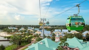 Disney Skyliner gondolas zip along a cable above Disney Resort hotel buildings