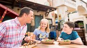 A family has lunch at an outside table in Harambe Market at Disney’s Animal Kingdom Theme Park A family has lunch at an outside table in Harambe Market at Disney’s Animal Kingdom Theme Park