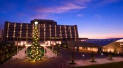 Un árbol de Navidad encendido frente al Disney’s Contemporary Resort iluminado por la noche Un árbol de Navidad encendido frente al Disney’s Contemporary Resort iluminado por la noche