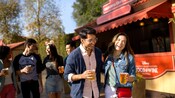 A couple, carrying their beers and laughing together in front of a craft brew cart