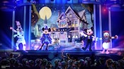 An artist rendering of Goofy, Minnie, Mickey and Donald performing on stage in Halloween costumes