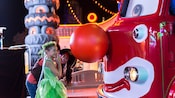 A little girl wearing a Tinkerbell costume and her mom look at a truck wearing a huge clown nose in Cars Land
