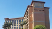 The exterior of a hotel with large windows on the upper floor and “Delta Hotels” on the side of the building