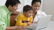 A smiling mother, father and young son looking at the screen of an open laptop computer