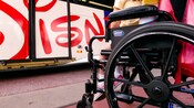 Close-up of wheelchair with a child as passenger, near lift entrance of a Disney bus