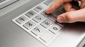 Close-up of fingers pressing numbers on an ATM keypad