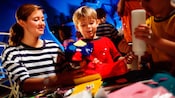A young boy and a Cast Member admire the boy's craftwork