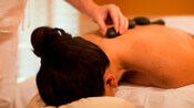 Woman on a massage table having warm stones applied to her back