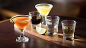 3 shots of various tequilas next to 2 glasses containing two types of margaritas
