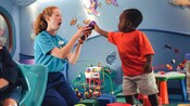 At Flounders Reef Nursery, a boy plays a game with a Cast Member in a room adorned with sea horses