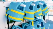 Eight toddler sized pool vests hanging on horizontal poles