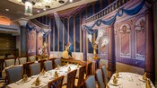 Three elegant dining tables next to a mural of a scene from the Disney film Beauty and the Beast