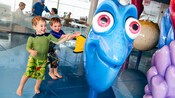 Two small boys have fun as they receive sprays of water from one of the Nemo character water features