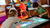 En la sala de la cabina de mando con temática oceánica, Wheelhouse, en el Disney’s Oceaneer Lab, los niños juegan videojuegos interactivos de alta tecnología
