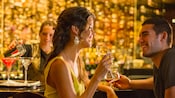 A woman with a glass of wine smiles at the man next to her