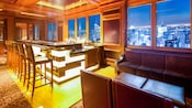 An elegant bar with high back stools near a lounge area with sofas and cocktail tables