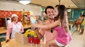 Un hombre le entrega a una niña un batido de leche en una tienda