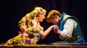 Flynn Rider and Rapunzel hold hands while bowing their heads to each other