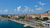 A marina full of boats near a boardwalk and a city