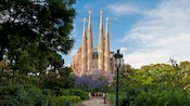 Sagrada Familia church in Barcelona, surrounded by trees and lush foliage