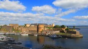 Un paseo marítimo con botes cerca de los muros del castillo y una mansión