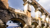 Crumbling stone arches stand against a cloudy sky