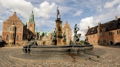 Statues of people playing instuments spout water into a fountain
