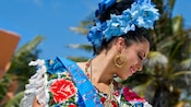 Profile of a woman with a headdress of flowers, flashy jewelry and other traditional festive garb on