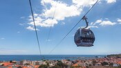 A cable lift carrying a passenger over an old village