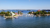 Trees cover two islands with buildings and docks between them in a large bay