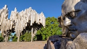 An art installation of vertically suspensed cylinders clumped together and a statue of a face