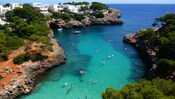 Sun worshippers float around a cove flanked by Ibiza's rocky shores and the Mediterranean Sea