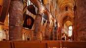 Dentro de una gran iglesia de ladrillos con techos abovedados, vitrales, columnas de piedra y bancas de madera