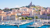 The Basilique Notre Dame de la Garde towers above Marseilles, with private yachts docked in the harbor