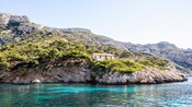 A lone home sits on the rocky shores of Marseilles, France, surrounded by lush trees