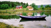 A long boat sits in the water with rope leading from either end
