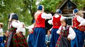 Young women in traditional Norweigan dresses dancing