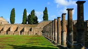 Stone pillars in varying states of disrepair surround a grass field