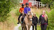 Young girl riding horseback down a trail with 3 other women