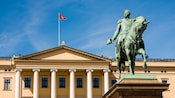 Statue of a man riding horseback in mililarty garb infront of large building with pillars