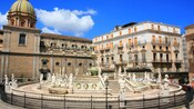 Edificios grandes con ventanas detrás de una fuente cerrada rodeada de estatuas