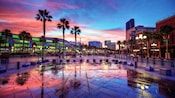 Palm trees and parking barricades in front of a modern looking shopping area at sunset