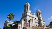 A large old church with dome shaped steeples and palm trees