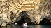 Two small motor boats heading into a large cave