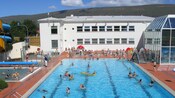Niños y adultos en un área de piscina equipada con un tobogán de agua en espiral