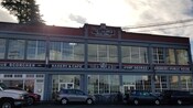 Parked cars near a building with signs that read Fort George Building, Scorcher, Bakery and Café, Fort George and Brewery + Public House